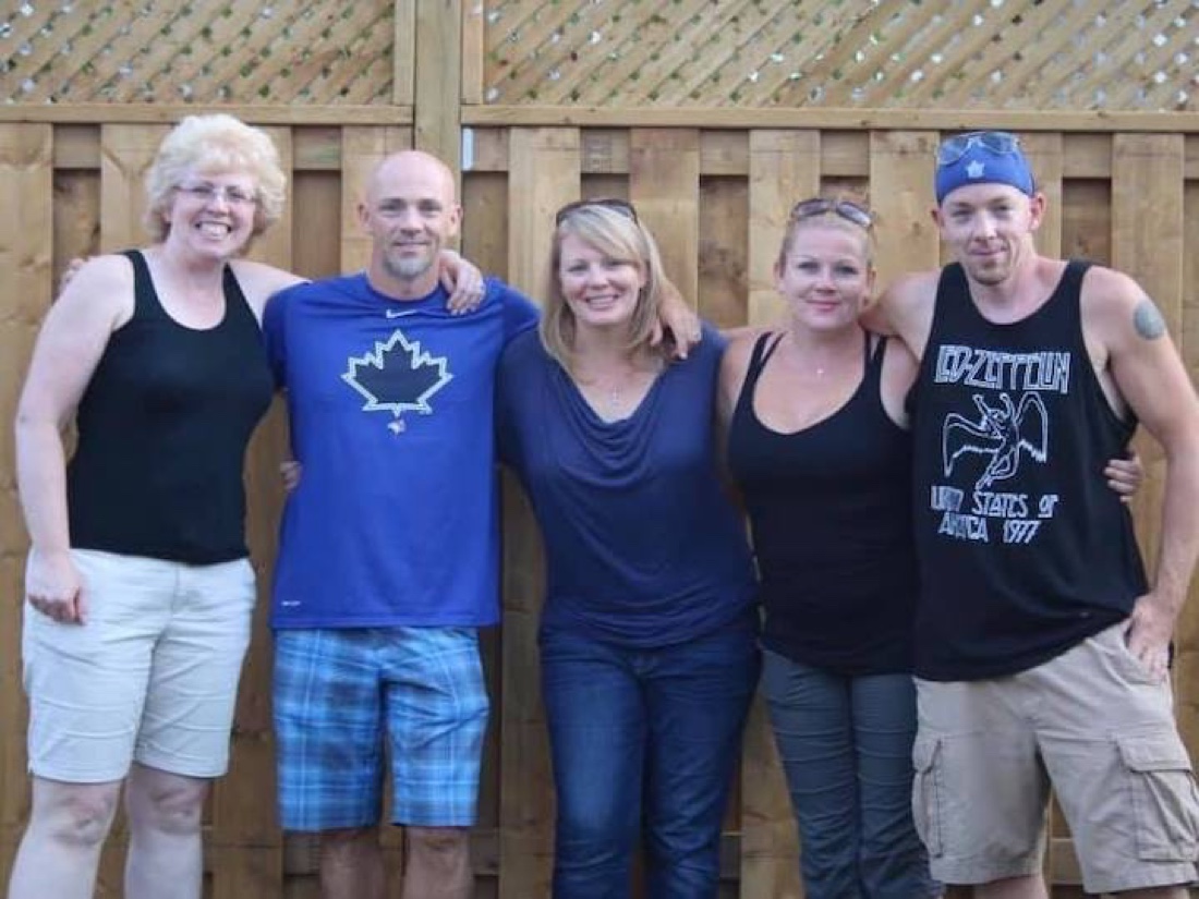 Five siblings standing together outdoors with their arms around each other