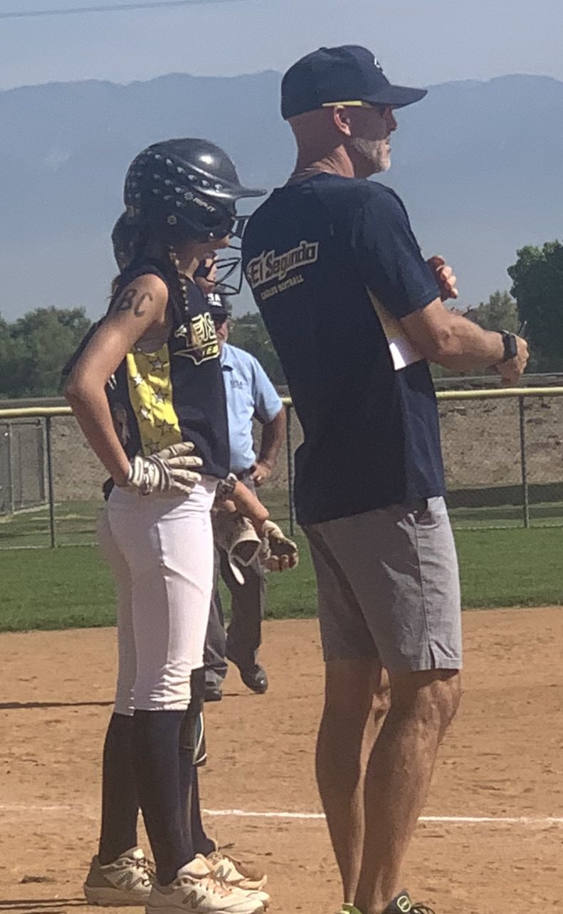 An Eagles player in her helmet standing on the base beside Steve Cleland, BC written on her arm