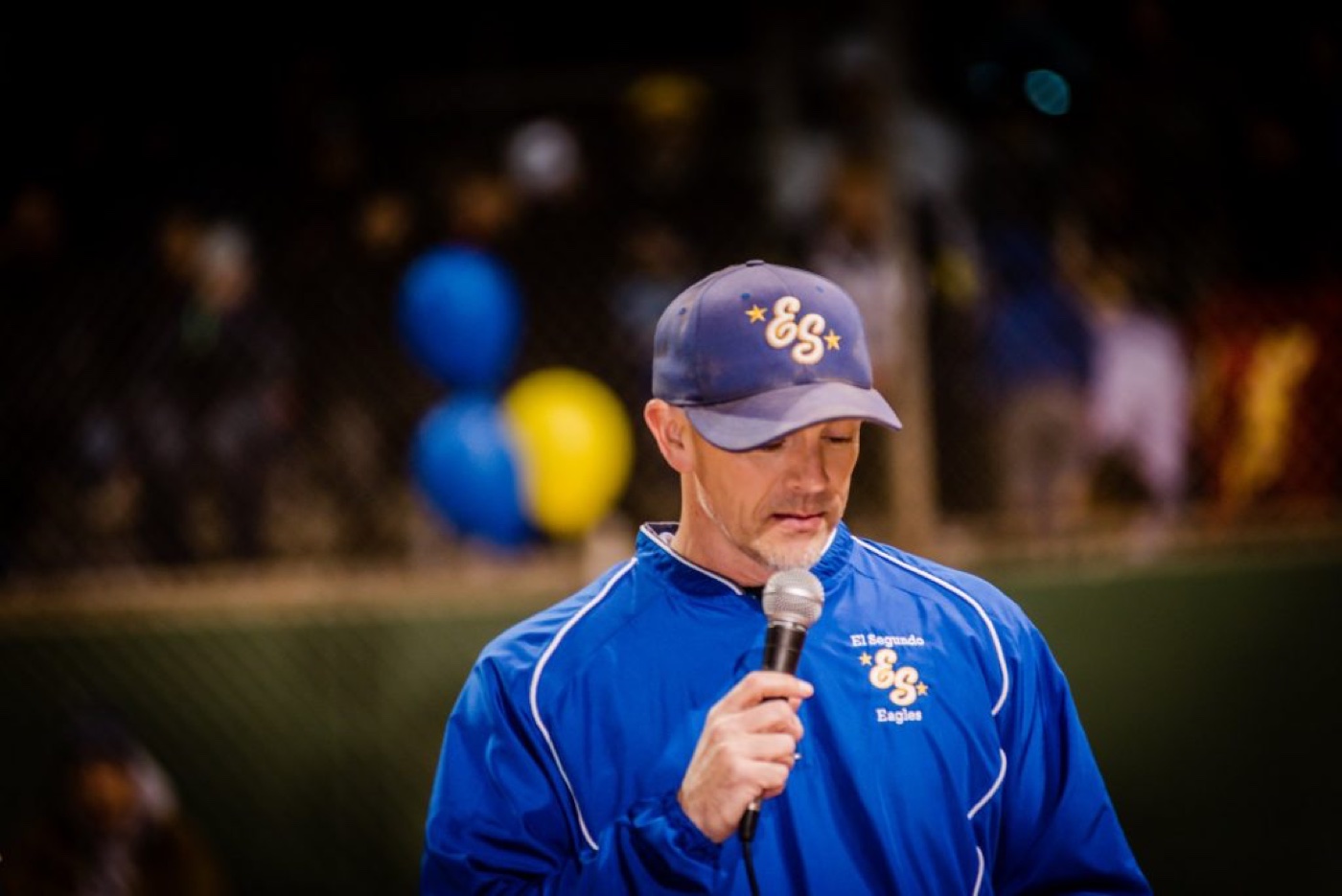 Steve Cleland speaking with a microphone at a ballfield event